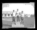 Trois détenus posent sur un podium lors de compétitions sportives tenues au Centre fédéral de formation dans les années 1950